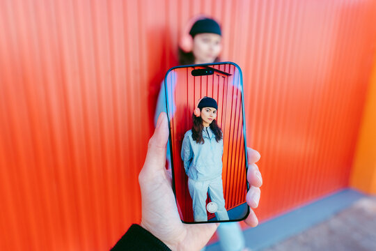 Woman Posing In Front Of Colorful Red Wall Seen Through Phone Screen