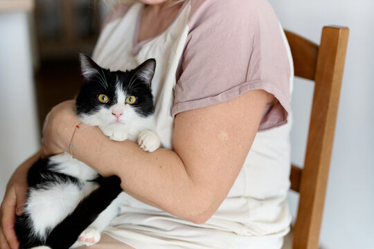 Woman Holding Black and White Cat at Home