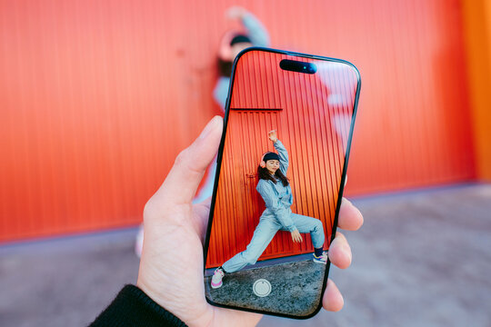 Woman Dacing In Front Of Colorful Red Wall Seen Through Phone Screen