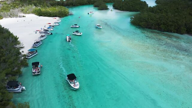 Boats gently cruise through clear blue waters alongside lush mangroves and white sand beaches. Ideal for depicting coastal leisure and marine activities.