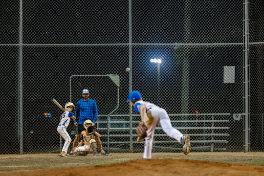 focused baseball coach watching kids practice