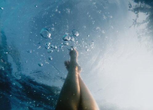 Gloomy underwater mood. Legs of someone floating under the surface.