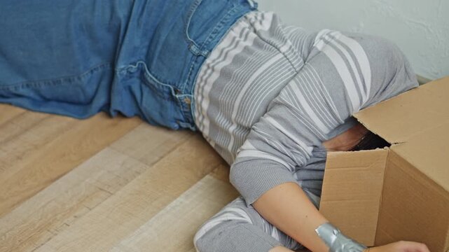 Bound female captive with head covered by cardboard box