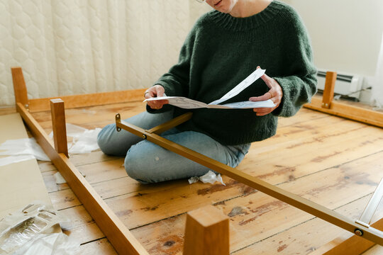Anonymous woman putting bed together with instructions
