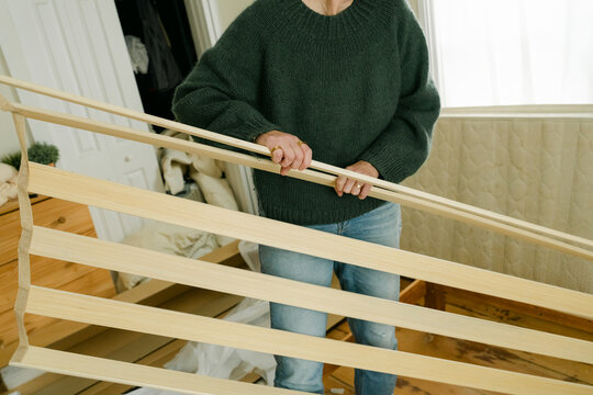 Anonymous woman putting slats of bed together 