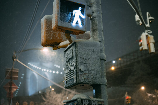 Snow Covered Walk Signal with Brooklyn Bridge at Night