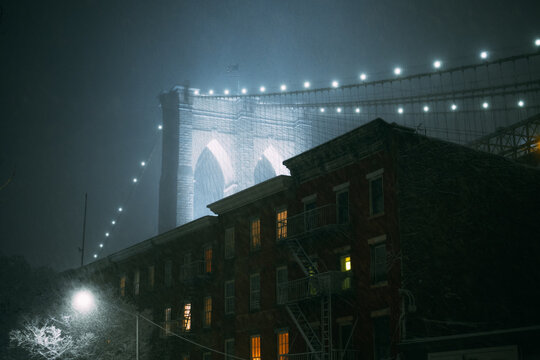 Brooklyn Bridge Above Brick Building on Foggy Winter Night