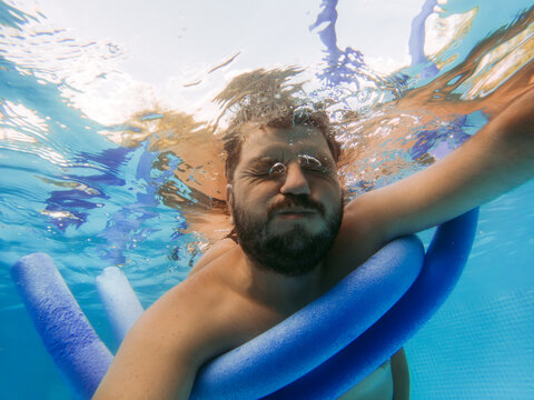 Adult man learning to swim. He is under the water with his eyes closed