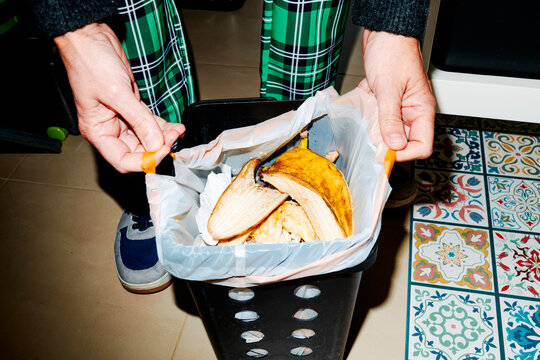 a man ties a full compost bag on the kitchen floor