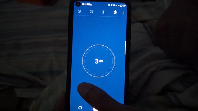 Clock ticking countdown timer app on smartphone screen with blue background and visible finger interaction for timekeeping and scheduling concept.