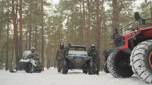 Red atv powers through snowy trail with lone rider. Camouflaged pilot accelerates on bright red quad across packed snow, chunky tires throwing powder, pine forest backdrop and motion blur convey speed