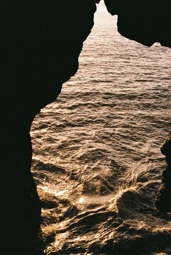 Golden ocean waves framed by volcanic rock cliffs