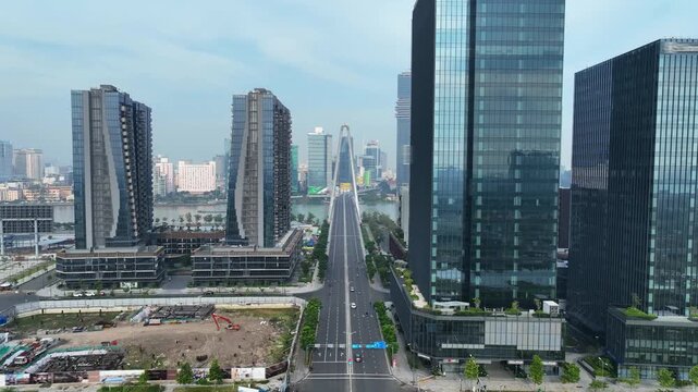Urban boulevard framed by modern high-rise buildings leading toward iconic bridge, showcasing planned city infrastructure in Ho Chi Minh City.