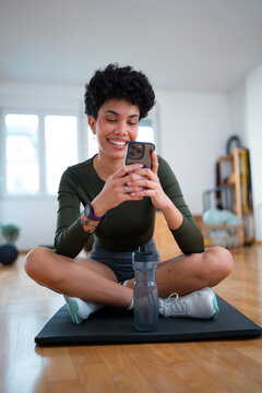 Woman checking smartphone during workout break in fitness studio