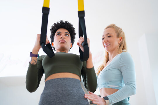Personal trainer guiding suspension training