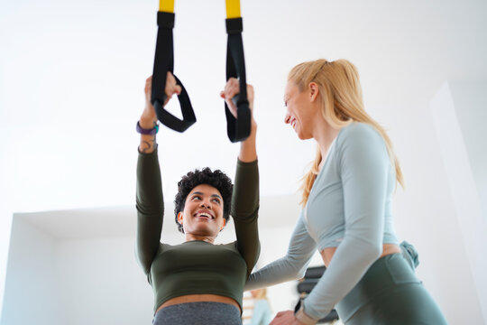 Personal trainer guiding client during suspension training