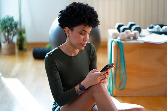 Woman using phone in a fitness space