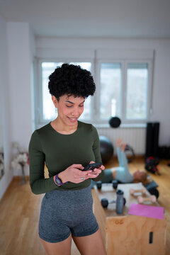 Smiling woman using phone in workout space