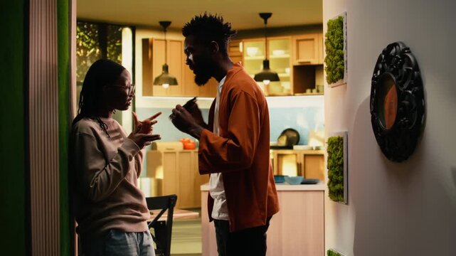 Jealous offended man controlling smartphone and worrying about dishonesty or infidelity, obsessive boyfriend starting a fight with girlfriend. Toxic relationship with suspicion and distrust.