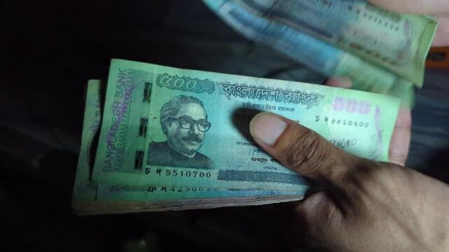 Man counting Bangladeshi taka 500 banknotes in a stack slow motion close up detail currency financial transaction exchange economy rich wealth banking paper money exchange service concept.