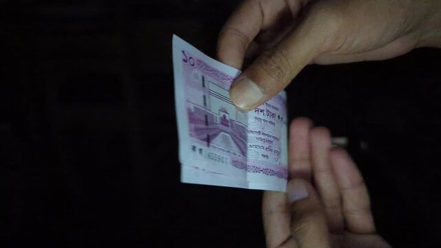 Two Bangladeshi 10 taka banknotes held in hands showing monetary value and national currency symbols with detailed security features and design elements in motion.