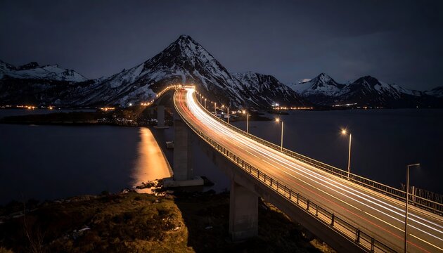 Long exposure shot of a bridge with car light trails at night. Mountains and water surround the structure