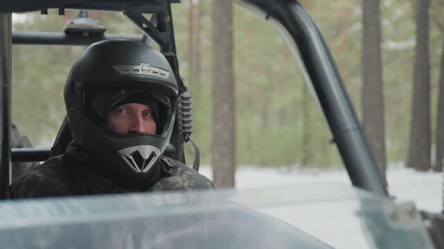 Helmeted male adventurer driving atv through snowy pine forest, visible smile through visor, steady throttle, tracks cutting powder, sunlight slanting through trees, exhilarated mood