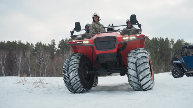 Closeup of snow covered atv tire with caucasian rider prepping for extreme run, orange rim detail, deep tread packed with frost, low angle shot emphasizing traction and mechanical strength