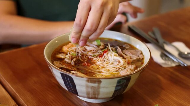 Vietnamese Person Squeezing Fresh Lime Into a Bowl of Bun Cha