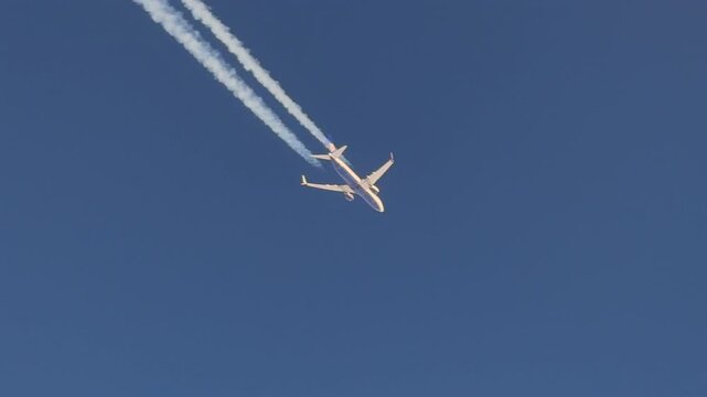 twin-engine jet airplane and its fading contrail in a deep blue sky, as viewed from another jet cokcpit flying 600m bellow in the same track.