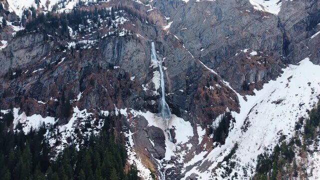 Aerial: Engstligen Falls with snow during the day, second highest fall in Switzerland, jib up drone shot, wide shot