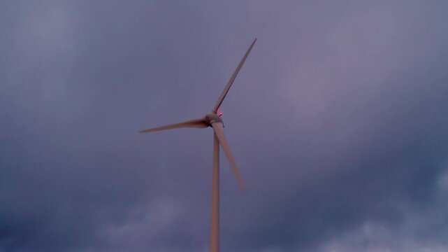 Wind turbine horizontal axis type on Serra da Boneca ridge in Centro region Portugal overlooking Mondego River valley at sunset rotating and producing energy, static silhouette shot