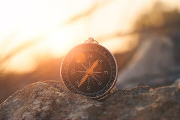 Silhouette the compass rests on a rock by the sea at sunset. © r_tee
