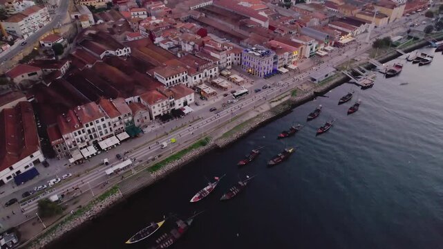 Rabelo boats along Douro River at Vila Nova de Gaia waterfront on Av de Diogo Leite in Porto municipality Porto district Norte region Portugal with road traffic, drone oblique glide shot