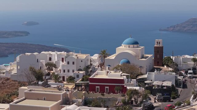 Drone revealing the steep vertical cliffs and Imerovigli houses in Santorini, showcasing the dramatic caldera landscape and the deep blue Aegean Sea.