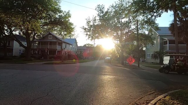 Sideways motion along a peaceful street at sunset with scenic trees and countryside vibes