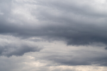 Obraz premium Heavy gray clouds gather above horizon. Overcast sky with threatening storm clouds looming overhead. Foreboding storm clouds cast dark and dramatic atmosphere across sky