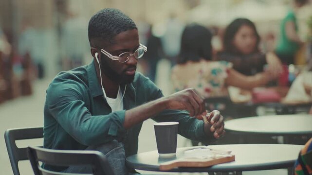 Male figure seated outside as he prepares his meal amidst lively street chatter and vibrant clothing