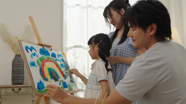 Happy Asian family painting a large artwork together
