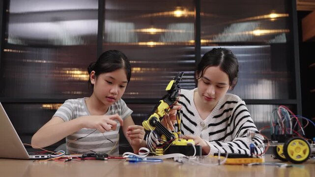 Multiracial girls learning to build a robotic arm in class