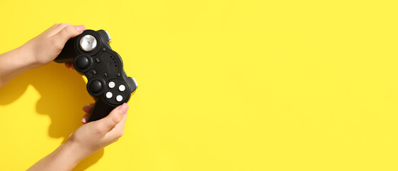 Female hands with modern game pad on yellow background © Pixel-Shot