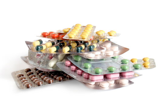 On a white background lies a pile of blisters with medicine tablets.