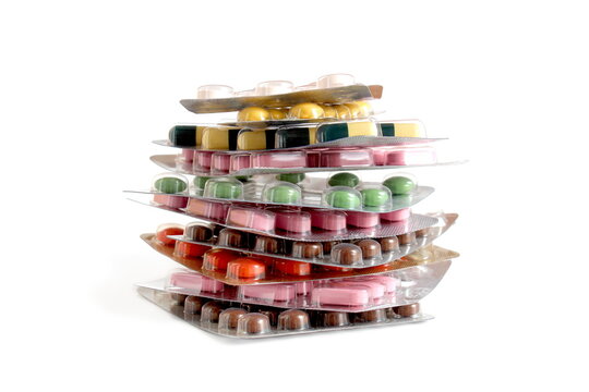 On a white background lies a pile of blisters with medicine tablets.