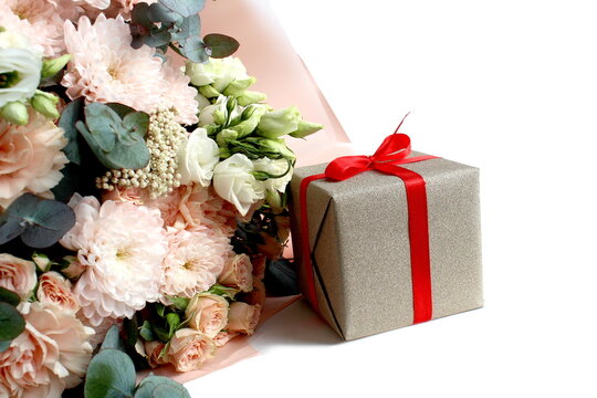 There is a bouquet of beautiful flowers with a gift box on a white background.