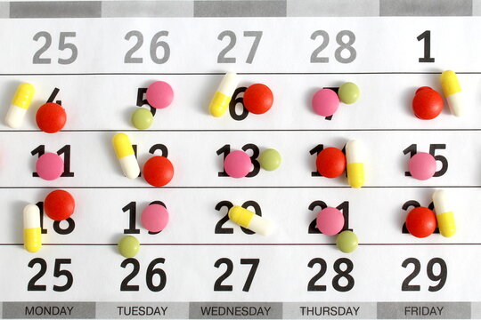 Texture of multi-colored medicine tablets and capsules lie on a white background.