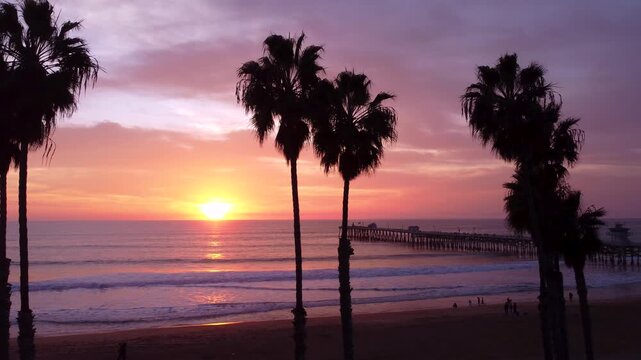 Pier Overlooking the Sunset on beach. Cinematic Silhouette of Palm Trees in the foreground. San Clemente, Orange County, California