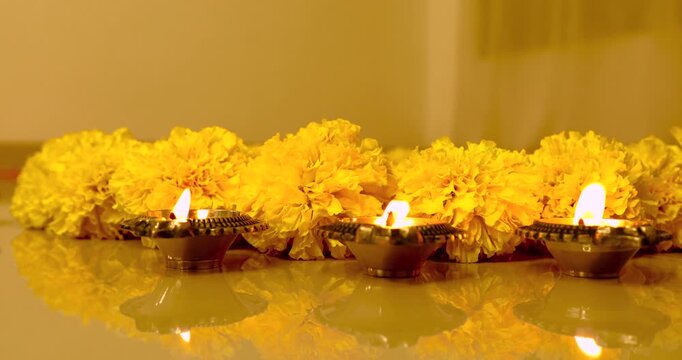 Close up of burning Oil Lamp Diyas during Diwali festival decorated with yellow marigold flowers.