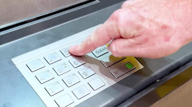 Close-up footage of a hand entering a PIN code on ATM keypad for financial transaction.