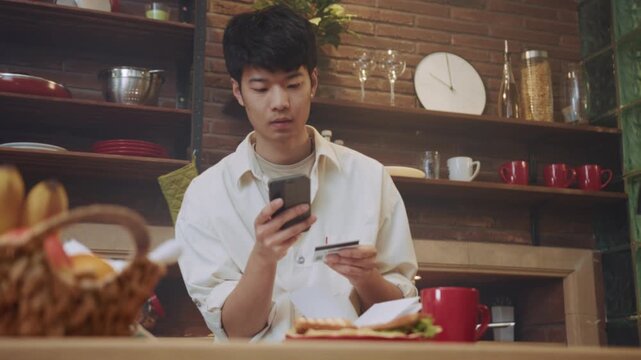 Man uses phone for payment, Asian male confidently finalizes breakfast order using mobile device and credit card