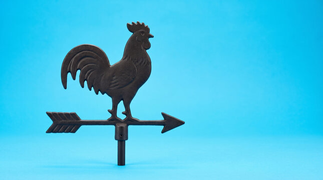 Iron rooster weather vane on sky blue surface climate wind direction forecast meteorology concept.